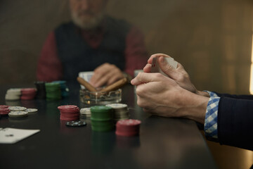 An intense poker game highlighted by chips, cards and players in a mysterious atmosphere