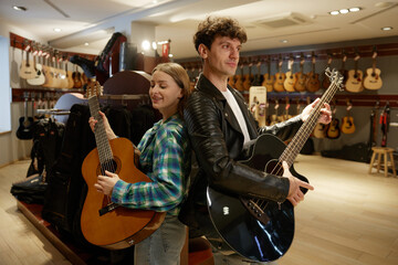In a music store, a man and a woman are playing their guitars skillfully