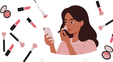 Woman applying makeup while looking at phone surrounded by makeup brushes and lipstick products scattered around