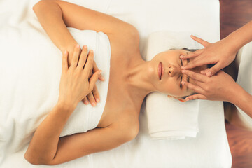 Panorama top view of woman enjoying relaxing anti-stress head massage and pampering facial beauty skin recreation leisure in dayspa modern light ambient at luxury resort or hotel spa salon. Quiescent