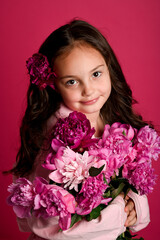 A joyful girl of Latina descent holds a vibrant bouquet of pink peonies against a hot pink...