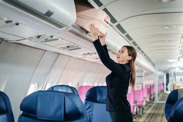 woman traveler putting luggage in overhead bin on airplane journey