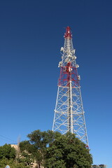 Upward view of a telecommunication tower against vivid blue sky. A dramatic upward shot of a...
