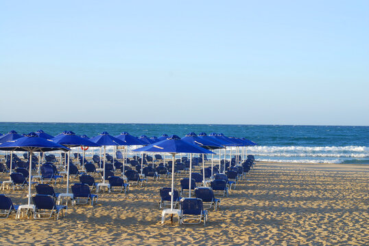 Empty sea beach with umbrellas and sun loungers at sunset.