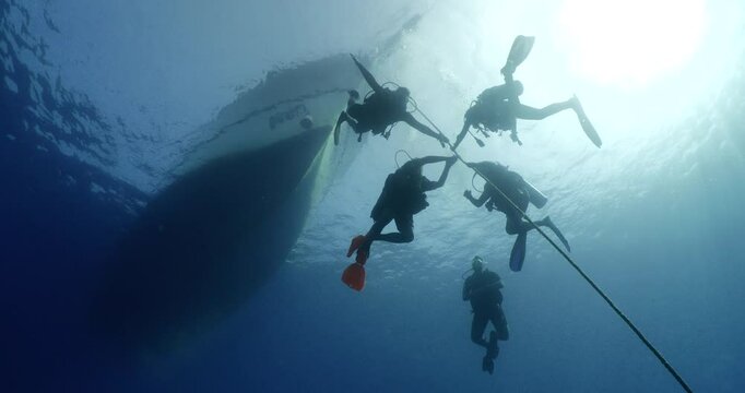 scuba divers fnishing dive doing safety stop on a rope underwater