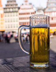 Glass of beer on a wooden table against the background of German half-timbered houses.