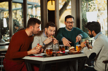 Male friends drinking and eating in the pub
