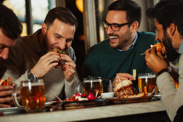 Male friends drinking and eating in the pub