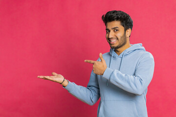 Indian bearded man showing thumbs up and pointing left empty place, advertising area for commercial...