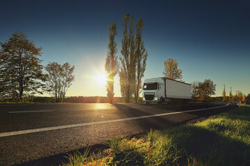 Large Transportation Truck on a highway road through the countryside at sunset
