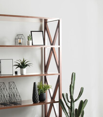 Industrial wood shelving unit with geometric iron frame, styled with minimalist decor including black vases, succulents, metal organizers, blank frames and sculptural cactus in bright interior.