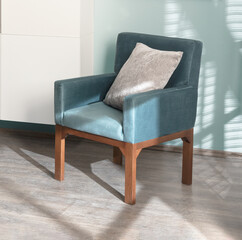 Teal velvet accent armchair with wooden legs and soft beige pillow, elegantly styled beside modern...