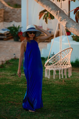 Woman in Blue Dress Walking Towards Outdoor Retreat

A woman in a flowing blue dress and striped...