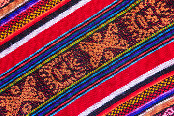 Colorful hand-woven Inca textile background with ancient designs from the Andes mountain range of...