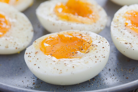 Soft boiled egg halves sprinkled with salt and pepper served on blue plate (Selective Focus, Focus one third into the image)