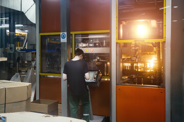 Worker operates automated blow molding machine