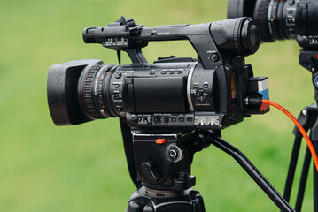 large black video camera on tripod outdoors, television work