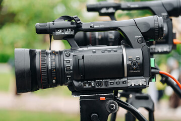 large black video camera on tripod outdoors, television work