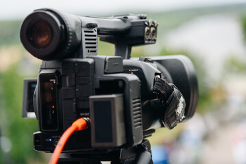 large black video camera on tripod outdoors, television work