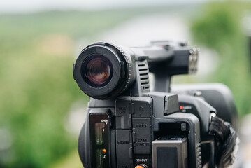 large black video camera on tripod outdoors, television work