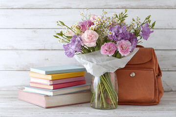 composition of book pile, school bag and a flower bouquet for the teacher on the Knowledge day on blurred background, copy space. 