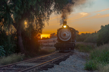 Vintage steam passenger train rounds bend at sunset