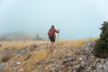 Hikers Exploring a Rocky Fog-Covered Mountain in the Morning Mist