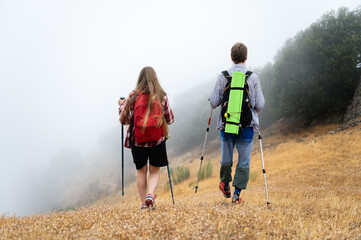 Two Hikers Navigating Through a Foggy Landscape in the Early Morning