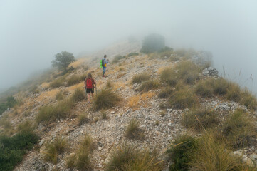 Obraz premium Hikers Exploring Rocky Terrain Amidst Morning Fog in Scenic Mountain Landscape