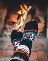 Obraz premium Close Up Of Feet In Colorful Socks Relaxing Near a Burning Fireplace
