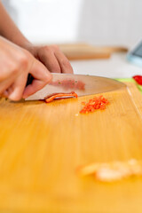 Chef cutting red pepper on wooden board, preparing peruvian ceviche