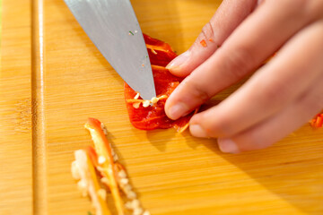 Chef removing seeds from chili pepper on cutting board