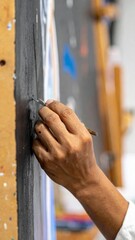 Close Up of an Artist Hand Painting a Dark Canvas with a Small Brush in Studio