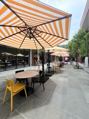 Sidewalk Cafe with Orange Striped Umbrellas on Grey Pavement