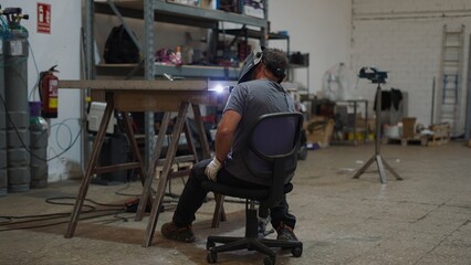 Welder using welding torch to join metal parts in a workshop, showcasing industrial manufacturing...