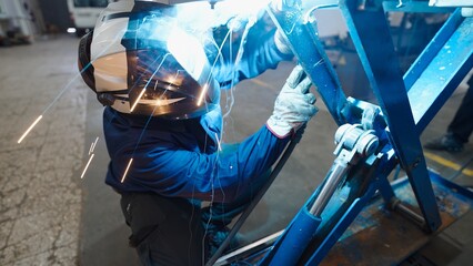 Experienced welder fusing metal parts with welding torch, highlighting precision manufacturing...