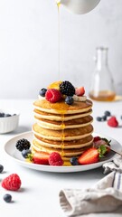 Stack of Pancakes with Fresh Berries Drizzled with Syrup on White Background
