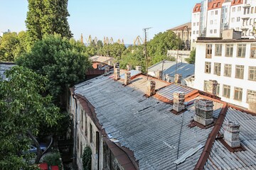 Old rooftop and residential buildings with visible decay and port cranes in the distance