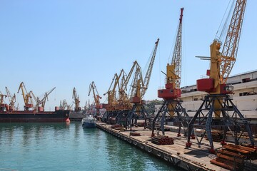 Industrial cargo port with dockside cranes and stacked steel pipes