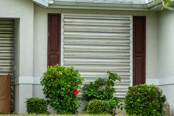 Storm shutters mounted on Florida house windows for hurricane protection. Preparing for natural...