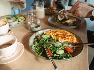 Close-up of a man and woman eating brunch with friends in a cafe