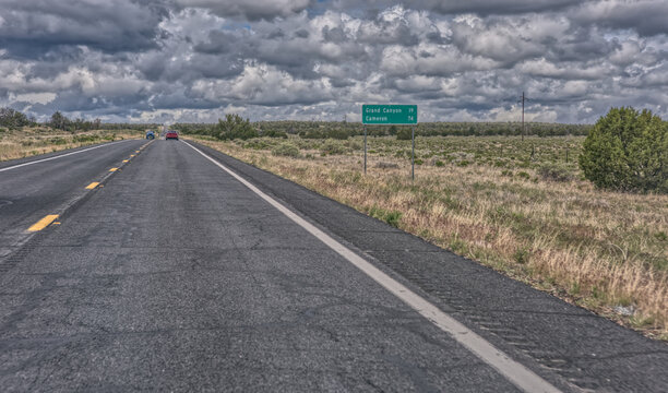 Cars driving along US Route 64 past a Grand Canyon Sign on an overcast day, Arizona, USA