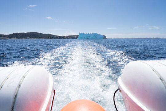 The stern of a boat and its wake sailing away from an iceberg, Twillingate, Newfoundland, Newfoundland and Labrador, Canada