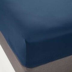 Solid navy blue fitted sheet on a bed with a neutral-toned mattress showing a cozy bedroom setup.