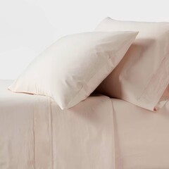 Obraz premium Soft pink bedding set with matching pillows in a cozy bedroom setting for a peaceful night's sleep.