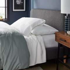 Comfortable bedroom setup featuring soft bedding and a stylish nightstand with decor.