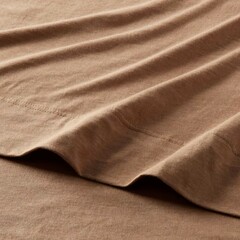 Soft brown fabric draped elegantly on a flat surface showcasing texture and color in a cozy setting.