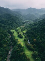 Elevated view of a golf course nestled in a valley, surrounded by lush mountains