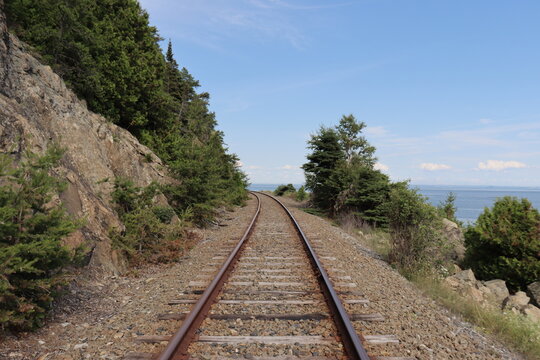 Railway in the countryside of Charlevoix in Quebec and in Canada. Summer landscape and horizon. Travel and destination and train transportation. Summer calendar with a view of a railway.