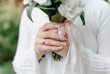 wedding bouquet in bride hands, white dress, green plants